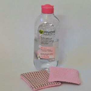 K&ouml;nnte beinhalten: Eine durchsichtige Plastikflasche mit Garnier SkinActive Micellar Cleansing Water. Die Flasche hat einen rosafarbenen Deckel und ein wei&szlig;es Etikett mit dem Produktnamen und der Beschreibung. Die Flasche steht auf einer wei&szlig;en Oberfl&auml;che mit zwei rosa-wei&szlig;en T&uuml;chern.