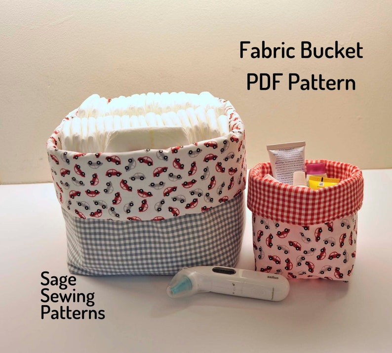 Puede incluir: Un patr&oacute;n PDF para un cubo de tela con estampado de coches rojos. El cubo est&aacute; lleno de pa&ntilde;ales y un cubo m&aacute;s peque&ntilde;o con estampado de coches rojos est&aacute; lleno de art&iacute;culos para beb&eacute;s. El texto "Fabric Bucket PDF Pattern" est&aacute; en la parte superior de la imagen y "Sage Sewing Patterns" est&aacute; en la parte inferior.