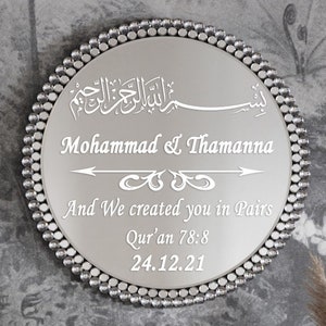 May include: A silver round mirror with a beaded border. The mirror has an inscription in Arabic script, followed by the names "Mohammad & Thamanna" and the text "And We created you in Pairs Qur'an 78:8 24.12.21".