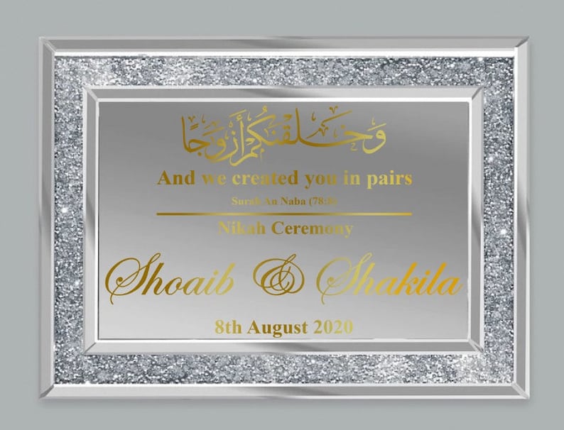 May include: A silver framed mirror with a glittery border. The mirror has a gold inscription that reads "And we created you in pairs, Surat an Naba (78:8)". Below the inscription is the text "Nikah Ceremony" and the names "Shoaib & Shaikila" with the date "8th August 2020".