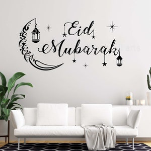 Op de afbeelding: Zwarte en witte wanddecoratie met de tekst "Eid Mubarak" en een halve maan met sterren en lantaarns.