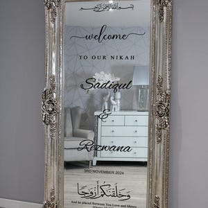 May include: A silver ornate mirror with a welcome sign for a wedding. The sign reads "Welcome to our Nikah Sadiqul & Rezwana 3rd November 2024" and includes an Arabic inscription that translates to "And he placed between you love and mercy [Quran 30:21]"