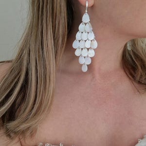 Puede incluir: Elegantes pendientes de araña con una cascada de cuentas blancas en forma de lágrima. Los pendientes cuelgan de un gancho plateado y crean un efecto glamuroso y llamativo. Perfectos para ocasiones especiales o para añadir sofisticación.