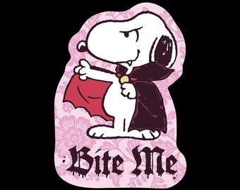May include: A sticker featuring a white cartoon dog dressed as a vampire in a black cape with a red lining, set against a light pink floral background. The text Bite Me is printed in a black gothic font with a dripping effect at the bottom.