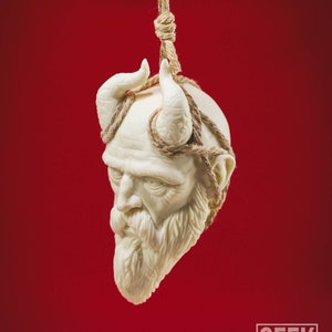 May include: A white ceramic sculpture of a man's head with horns and a beard, tied with twine and hanging from a rope against a red background.