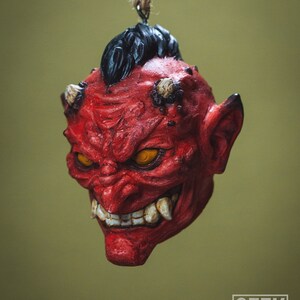 May include: A red and black demon mask with a menacing expression, hanging from a string. The mask has sharp teeth, glowing yellow eyes, and horns.