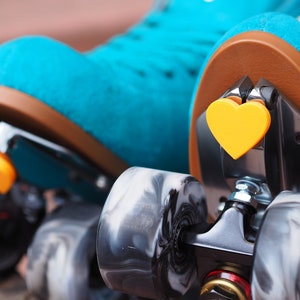 May include: A pair of teal roller skates with black wheels and yellow heart-shaped toe stops. The wheels have a marbled pattern.