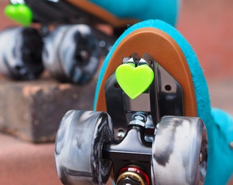 Pode incluir: Close-up de um par de patins de rodas azuis com rodas pretas e pingentes em forma de coração verde. As rodas têm um padrão de mármore.