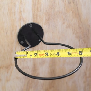 Puede incluir: Portavasos de pared de metal negro con una cinta m&eacute;trica amarilla que muestra una medida de 12,7 cm.