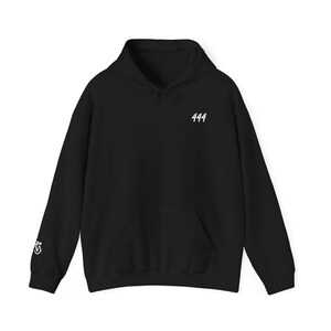 Könnte beinhalten: Schwarzer Kapuzenpullover mit Fronttasche und Kordelzug. Die Zahl "444" ist weiß auf der oberen Brust aufgedruckt. Auf dem linken Ärmel befindet sich eine kleine Grafik.