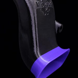 Puede incluir: Una pieza automotriz negra curvada con un borde morado. La pieza tiene una superficie texturizada y el texto "MTS Perf" es visible. El fondo es negro.