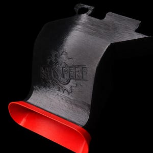 Peut inclure: Un conduit d'admission d'air automobile noir imprimé en 3D avec une ouverture rouge en forme d'entonnoir à l'avant. Le corps principal présente un emblème en forme d'engrenage avec le texte en relief "MIS PERF" sur la surface incurvée.