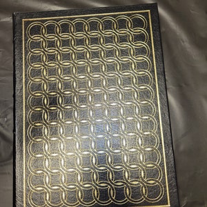 May include: A black leather-bound book with a gold embossed pattern of interlocking circles.