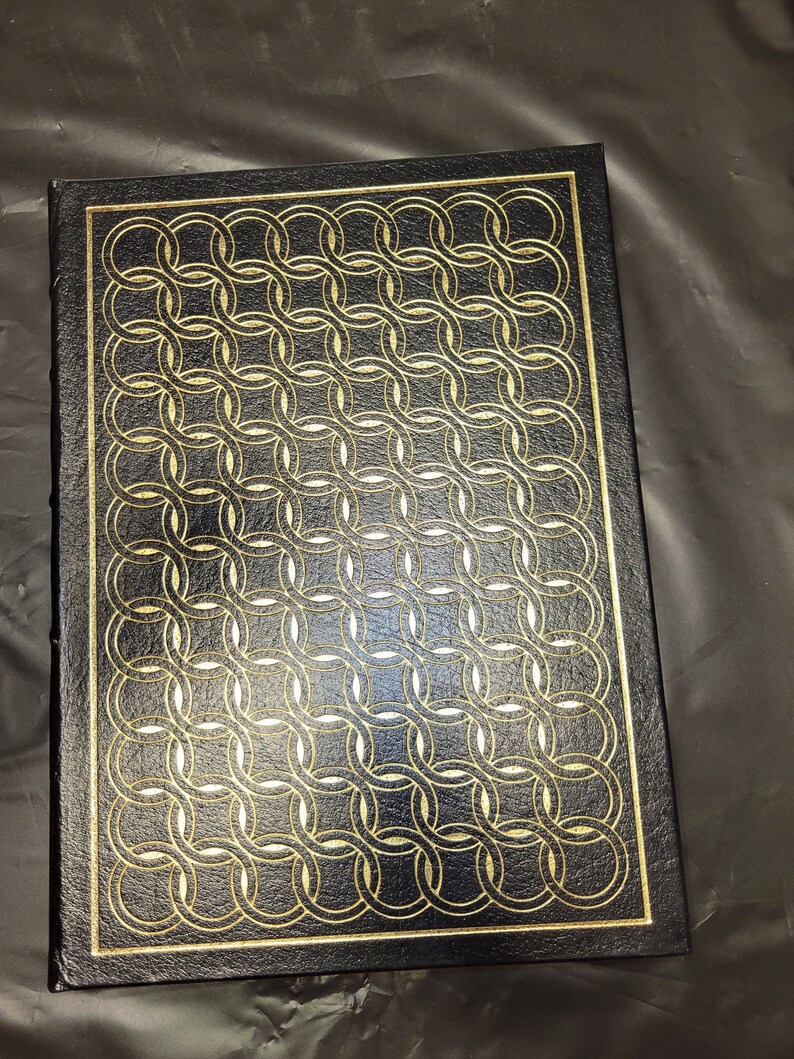 May include: A black leather-bound book with a gold embossed pattern of interlocking circles.