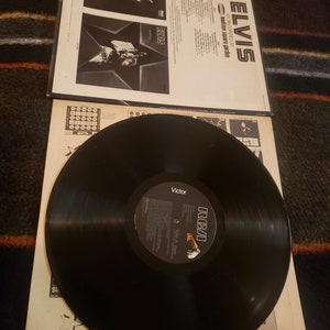 May include: A black vinyl record with a white RCA label. The record is titled "Elvis As Recorded At Madison Square Garden". The album cover features a black and white photo of Elvis Presley.