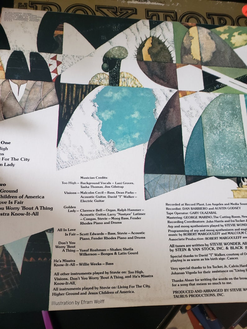 Puede incluir: La contraportada de un &aacute;lbum de vinilo para el &aacute;lbum "Children of America" de Stevie Wonder. La portada del &aacute;lbum presenta un dise&ntilde;o geom&eacute;trico abstracto en tonos de azul, verde, marr&oacute;n y blanco. Los cr&eacute;ditos del &aacute;lbum enumeran los m&uacute;sicos que tocaron en el &aacute;lbum, incluidos Stevie Wonder, Malcolm Cecil, Clarence Bell y Yusuf Roahman. El &aacute;lbum fue producido y arreglado por Stevie Wonder y Taurus Productions, Inc.