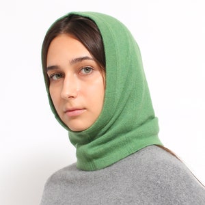 May include: A green knitted neck warmer or snood with a fold-over design. The neck warmer is made of a soft, comfortable material and is perfect for keeping warm in the winter.
