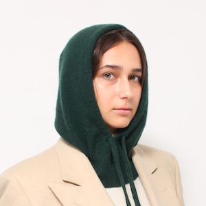 Peut inclure: Une femme portant un cache-cou à capuche vert foncé sur un blazer beige. Le cache-cou a un cordon.