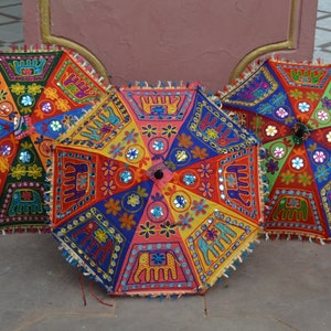 Puede incluir: Tres paraguas coloridos con bordados intrincados y adornos de espejo. Los paraguas est&aacute;n hechos de tela y tienen un dise&ntilde;o tradicional indio.