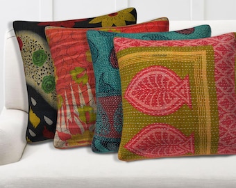 May include: Four decorative throw pillows with colorful, patterned fabric. The pillows feature a variety of designs, including floral and geometric patterns, in shades of red, green, blue, and yellow. The pillows are arranged on a white sofa.