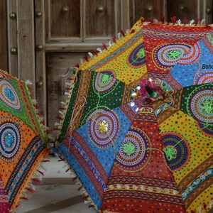 May include: Four colorful umbrellas with intricate patterns and embellishments. The umbrellas are made of fabric and have a variety of colors, including red, green, blue, yellow, and orange. The umbrellas are decorated with sequins, beads, and other embellishments.