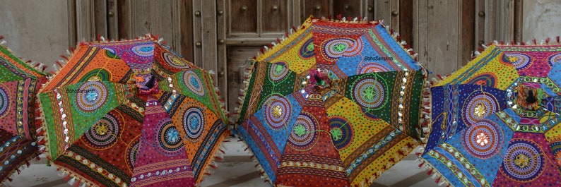 May include: Four colorful umbrellas with intricate patterns and embellishments. The umbrellas are made of fabric and have a variety of colors, including red, green, blue, yellow, and orange. The umbrellas are decorated with sequins, beads, and other embellishments.