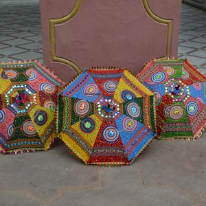 May include: Three colorful umbrellas with intricate embroidery and sequins. The umbrellas are made of fabric and have a traditional Indian design.