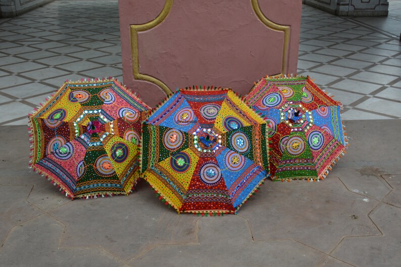 May include: Three colorful umbrellas with intricate embroidery and sequins. The umbrellas are made of fabric and have a traditional Indian design.