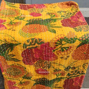 K&ouml;nnte beinhalten: Gelbe Kantha-Steppdecke mit einem floralen Muster in Rot-, Gr&uuml;n- und Oranget&ouml;nen. Die Decke ist handgen&auml;ht mit wei&szlig;em Garn und tr&auml;gt ein BohoSanskrit-Etikett.