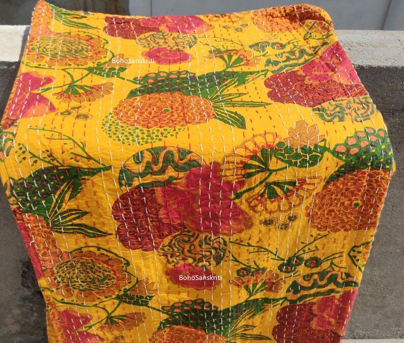 K&ouml;nnte beinhalten: Gelbe Kantha-Steppdecke mit einem floralen Muster in Rot-, Gr&uuml;n- und Oranget&ouml;nen. Die Decke ist handgen&auml;ht mit wei&szlig;em Garn und tr&auml;gt ein BohoSanskrit-Etikett.