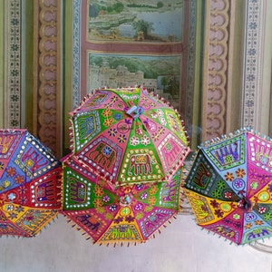 Puede incluir: Tres paraguas coloridos y estampados con bordados e incrustaciones intrincados. Los paraguas est&aacute;n hechos de tela y tienen un dise&ntilde;o tradicional indio.
