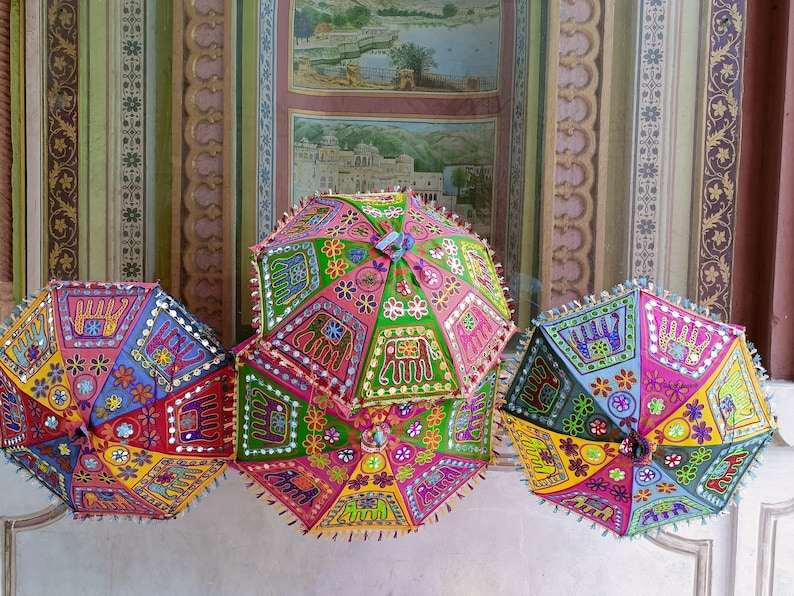 Puede incluir: Tres paraguas coloridos y estampados con bordados e incrustaciones intrincados. Los paraguas est&aacute;n hechos de tela y tienen un dise&ntilde;o tradicional indio.