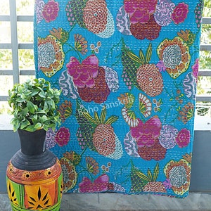 K&ouml;nnte beinhalten: Eine t&uuml;rkisblaue Kantha-Steppdecke mit einem floralen Muster in Rosa-, Orange-, Gr&uuml;n- und Wei&szlig;t&ouml;nen. Die Steppdecke ist handgen&auml;ht und hat einen Vintage-Look.