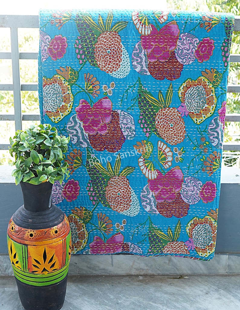 K&ouml;nnte beinhalten: Eine t&uuml;rkisblaue Kantha-Steppdecke mit einem floralen Muster in Rosa-, Orange-, Gr&uuml;n- und Wei&szlig;t&ouml;nen. Die Steppdecke ist handgen&auml;ht und hat einen Vintage-Look.