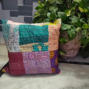 May include: A patchwork pillow with a variety of colors and patterns. The pillow features squares of teal, pink, purple, and other colors, stitched together with white thread. The text "BohoSanskriti" is visible on the pillow.