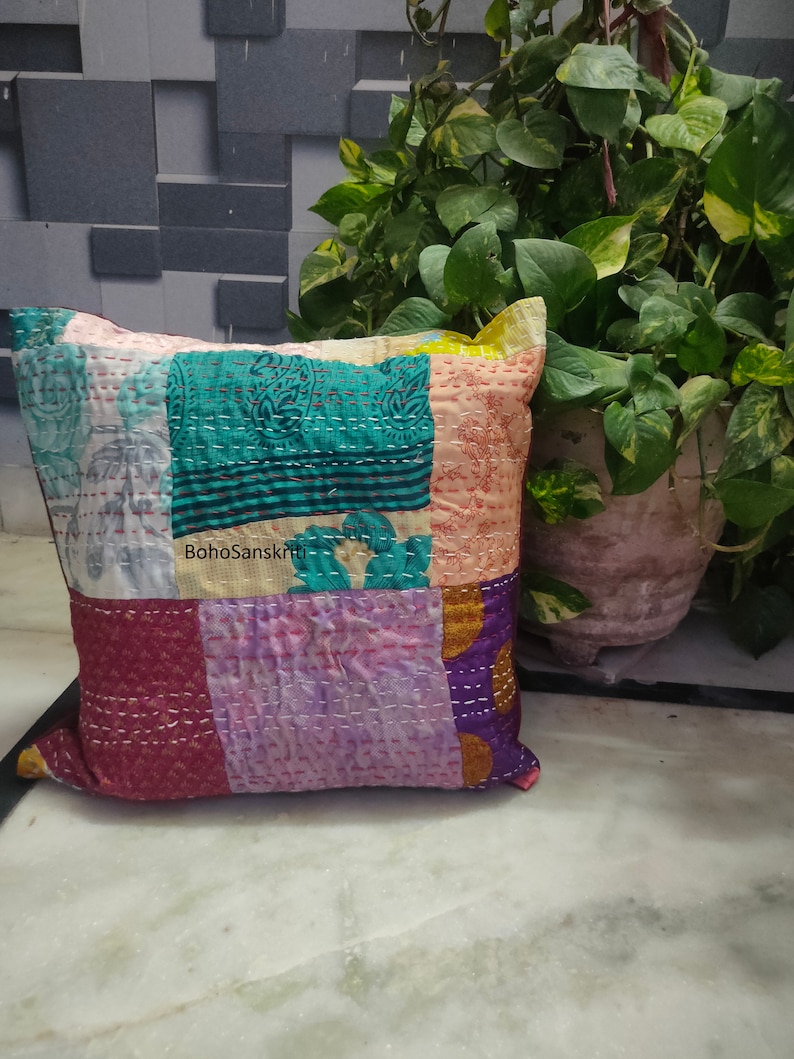 May include: A patchwork pillow with a variety of colors and patterns. The pillow features squares of teal, pink, purple, and other colors, stitched together with white thread. The text "BohoSanskriti" is visible on the pillow.