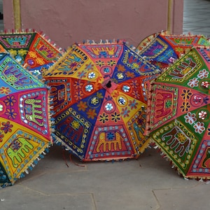 Puede incluir: Cuatro paraguas coloridos con bordados intrincados y adornos de espejo. Los paraguas est&aacute;n decorados con elefantes, flores y patrones geom&eacute;tricos. Los paraguas est&aacute;n hechos de tela y tienen un mango de madera.