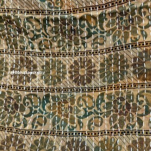 May include: A beige fabric with a repeating pattern of green and brown flowers. The fabric is stitched with white thread in a running stitch pattern. The fabric has a subtle sheen and a soft texture.