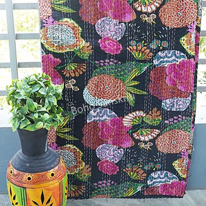 K&ouml;nnte beinhalten: Eine schwarze Kantha-Steppdecke mit einem farbenfrohen Blumenmuster. Die Steppdecke ist aus Baumwolle und hat ein handgesticktes Design. Die Steppdecke ist &uuml;ber einem Gel&auml;nder drapiert, im Vordergrund steht eine dekorative Vase.