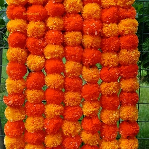May include: A garland of orange and yellow marigold flowers, also known as a "mala", is a traditional Indian decoration. The garland is made of paper and is perfect for adding a touch of colour and festivity to any occasion.