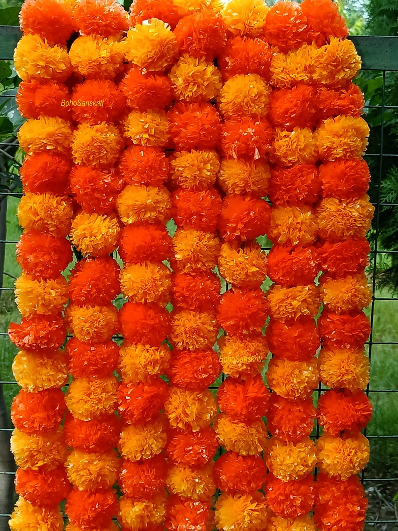 May include: A garland of orange and yellow marigold flowers, also known as a "mala", is a traditional Indian decoration. The garland is made of paper and is perfect for adding a touch of colour and festivity to any occasion.