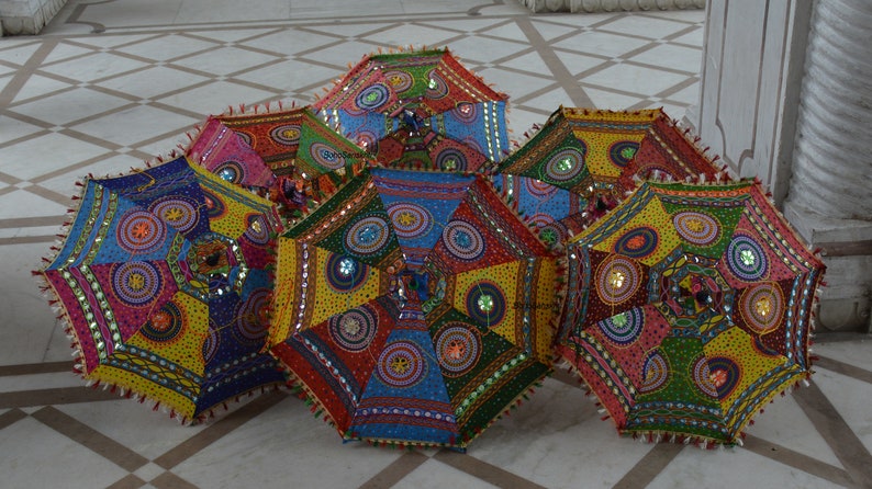 May include: Six colorful umbrellas with intricate patterns and embellishments. The umbrellas are made of fabric and have a variety of colors, including red, blue, green, yellow, and pink. They are decorated with sequins, beads, and other embellishments.