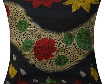 May include: Square decorative pillow with a black background and a floral design. The design features red, green, and yellow flowers with a cream-colored border. The pillow has a textured appearance.