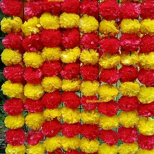 May include: A garland of alternating red and yellow fabric flowers. The flowers are arranged in rows and are attached to a string. The garland is ideal for decorating for a party or special occasion.