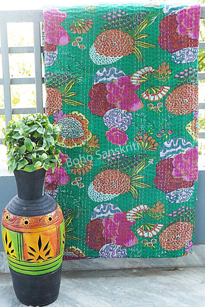 K&ouml;nnte beinhalten: Eine gr&uuml;ne Kantha-Steppdecke mit einem floralen Muster in Rosa-, Orange- und Lilat&ouml;nen. Die Steppdecke ist handgen&auml;ht und hat einen einzigartigen Vintage-Look.