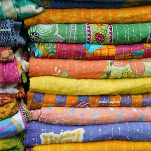 May include: A stack of colorful kantha quilts with floral and geometric patterns. The quilts are made of recycled saris and are hand-stitched. The text "Boho Sanskriti" is visible on two of the quilts.