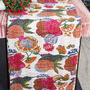 May include: White kantha quilt featuring a floral pattern in shades of pink, orange, green, and blue. The quilt is hand-stitched and displays a traditional Indian design.