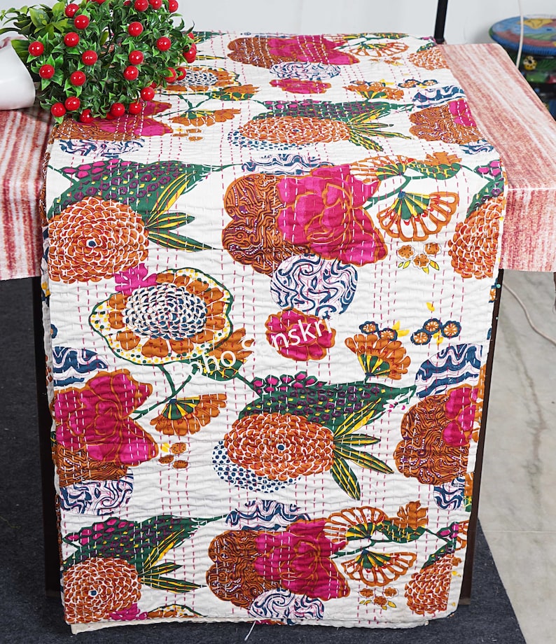 May include: White kantha quilt featuring a floral pattern in shades of pink, orange, green, and blue. The quilt is hand-stitched and displays a traditional Indian design.