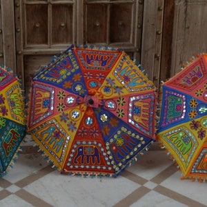 Puede incluir: Tres sombrillas coloridas con bordados intrincados y adornos de espejo. Las sombrillas est&aacute;n hechas de tela y tienen un dise&ntilde;o tradicional indio.