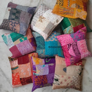 May include: A collection of nine colorful patchwork throw pillows with various patterns and textures. The pillows are made from recycled saris and are perfect for adding a touch of bohemian style to any room.